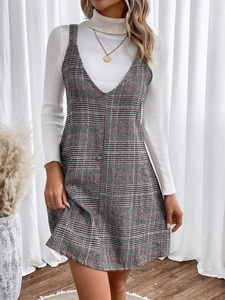 Detail of plaid suspender dress with white turtleneck sweater and gold necklace