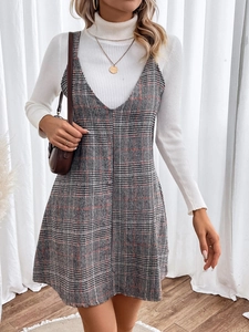 Detail showing red and grey plaid V-neck pinafore dress paired with white turtleneck top