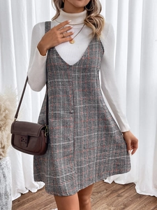 Detail of red-striped grey plaid pinafore dress paired with a white ribbed turtleneck