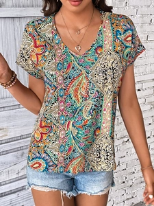 Détail du haut bohème à col en V avec motif paisley et colliers dorés à plusieurs rangs