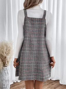 Rear view of a plaid pinafore dress with a white turtleneck knit sweater