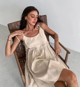 Detailed view of beige cotton linen dress with tie shoulder straps and pleated texture