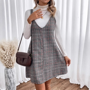 Plaid V-neck pinafore dress with white turtleneck knit top set in a cozy home setting