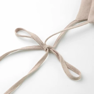Detailed close-up of beige cotton linen dress straps tied in a simple bow knot