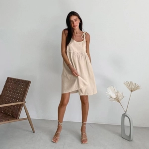 Detail of beige sleeveless tiered dress featuring adjustable tie-up shoulder straps