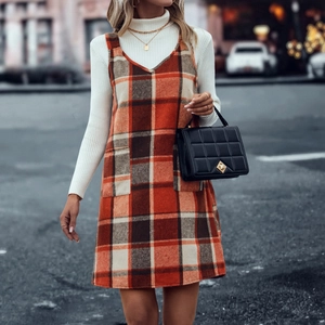 Detail des orangefarbenen Karokleids mit großen Taschen und einem Rollkragenpullover