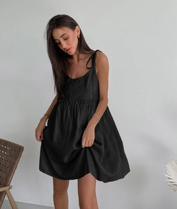 Detail showing self-tie shoulder straps and pleated waist on a black cotton linen dress