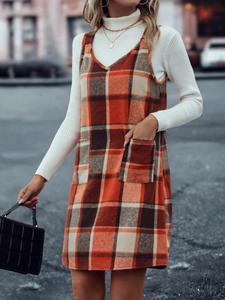Detail eines karierten Trägerkleids mit großen Taschen und weißem Rollkragenpullover
