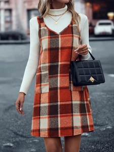 Detail eines orangefarbenen karierten Trägerkleides mit Taschen und Stepptasche