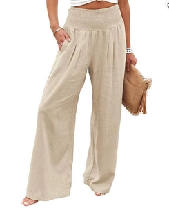 Detail of high waisted wide leg trousers in apricot linen blend with pleated elastic waist