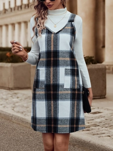 Detailansicht von kariertem Trägerkleid mit Taschen und weißem Rollkragenpullover
