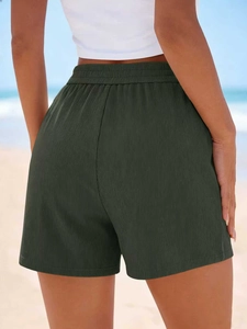 Détail du short en maille côtelée vert foncé à taille haute avec ceinture élastique sur plage