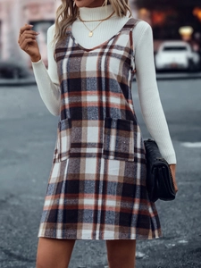 Detail von kariertem Trägerkleid mit Taschen und langärmeligem Rollkragenoberteil