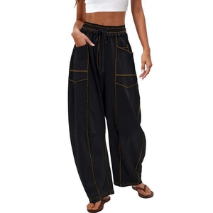 Detail of black wide-leg trousers with yellow contrast stitching and drawstring waist