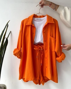 Detail of orange linen shirt texture with drawstring shorts and ribbed white tank top