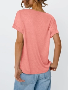 Close-up of coral pink T-shirt fabric with fixed rolled sleeves and soft cotton texture