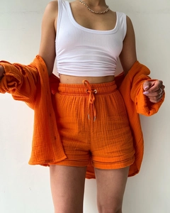 Detailed texture of orange crepe fabric set with high-waist drawstring shorts and vest