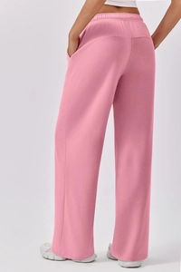 Detail view of pink wide-leg sweatpants showing elastic waistband and back pocket design
