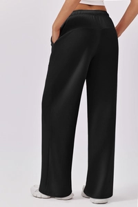 Detail view of black wide-leg sweatpants featuring an elastic waist and premium fabric texture