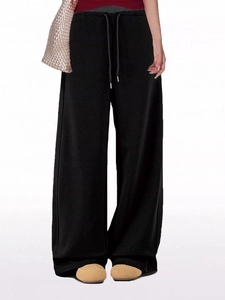Detail view of black wide-leg sweatpants with drawstring waist and loose vertical cut
