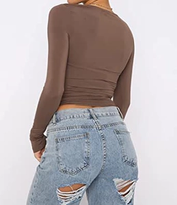 Detail of dark brown slim-fit long sleeve t-shirt with back ruching and ripped jeans
