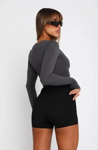Rear view of slim fit long sleeve top and high waist black shorts on model in studio