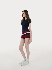 Side view of woman in navy blue slim-fit sports t-shirt and red drawstring shorts