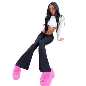 Detail view of black low-waist flared pants paired with bright pink faux fur slippers