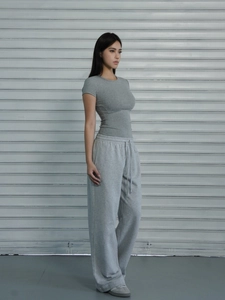 Side view of a slim fit gray sports t-shirt and loose joggers against an industrial backdrop