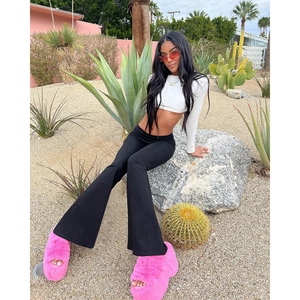 Detail shot of black high-waisted flared yoga pants paired with pink faux fur sandals