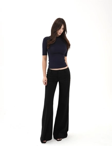 Detail of a slim-fit black knit top paired with high-waisted wide-leg trousers on model