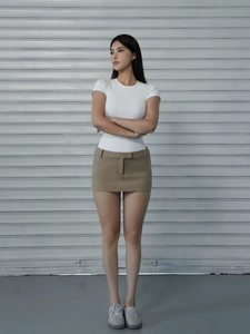 Close-up of white slim fit short sleeve t-shirt paired with a khaki mini skirt and sneakers