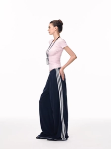 Detail of pink slim fit crew neck T-shirt with navy wide leg striped sports trousers