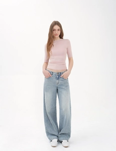 Full body view of a woman in a slim pink t-shirt and light blue wide leg jeans