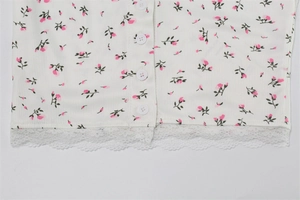 Detail of floral print knit fabric with white buttons and delicate lace hem trim