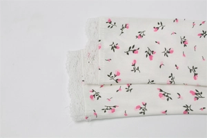 Detailed macro view of white ribbed knit fabric with pink floral print and lace edge