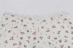 Close-up of white ribbed knit fabric with pink floral print and delicate lace trim detail
