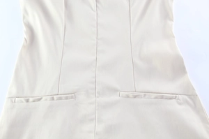 Detail of waist tailoring and pocket stitching on a beige slim-fit dress