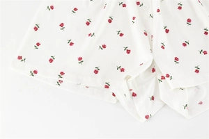 Détail du short blanc à côtes avec motif roses rouges et bouton blanc décoratif