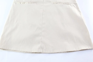 Detailed close-up of beige tailored skirt featuring symmetrical welt pockets and stitching