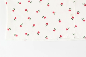 Détail de l'imprimé fleuri rose rouge sur tissu côtelé blanc avec bouton rond fini