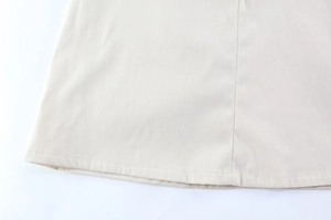 Detail view of the fine stitching and seam craftsmanship on the beige dress hemline