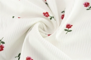 Gros plan sur un tissu côtelé blanc avec un motif floral de roses rouges délicates