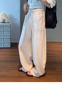 Close-up of cream high-waist drawstring trousers featuring large utility pockets