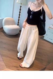 Detail of ivory wide-leg trousers showing elastic drawstring waist and side pocket texture