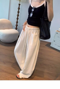 Detail of high-waist elastic drawstring on beige wide-leg trousers with textured fabric