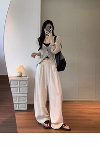 Detail of high-waisted off-white wide-leg trousers with large side pockets and relaxed fit