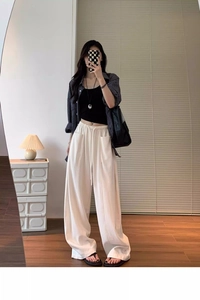 Detail view of high-waist beige wide-leg trousers paired with a black crop top and plaid shirt