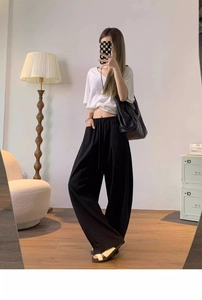 Detail of high-waisted black wide-leg pants featuring elastic waistband and drawstring