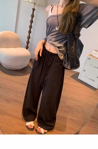 Detail of loose black wide leg trousers featuring a drawstring elastic high waistband